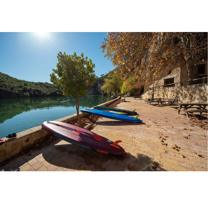 Neva 12.6 Inflatable Paddle Board being dried under the sun outside a brick-stone building near a lake