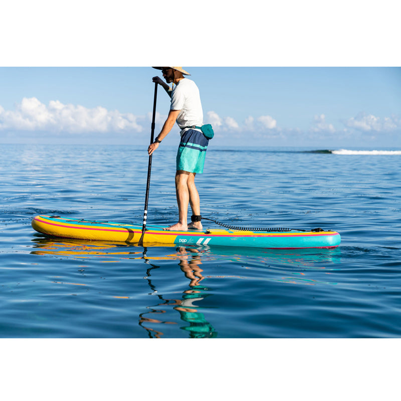 Yacht Hopper SUP Turq/Pink/Yellow on the water with a man paddleboarding atop.