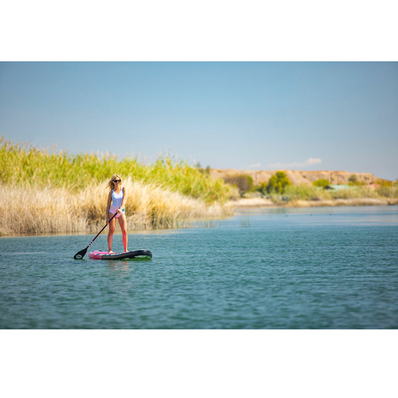 Royal Hawaiian SUP Pink-Black on the water with a woman paddleboarding on top.